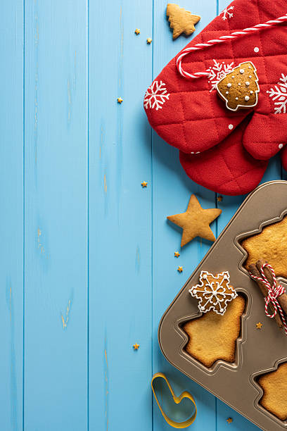 istock Vibrant vertical Christmas and New Year themed baking setup on a bright blue background featuring red quilted mitts, star cookies, gingerbread, and a cookie mold ready for decorating 2244780535