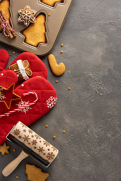istock A top view vertical cozy Christmas baking setup features a metal cookie tray, star and snowflake cookies, a patterned rolling pin, red oven mitt, and festive decorations 2244780545
