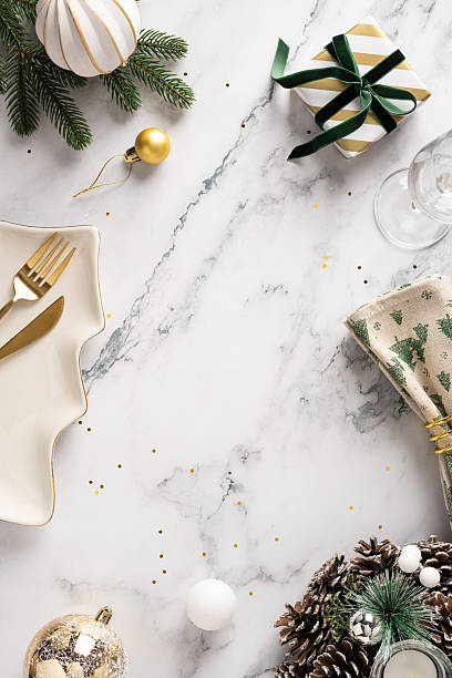 istock A vertical festive Christmas and New Year scene featuring wrapped presents, gold and white ornaments, pinecones, a gold plate, and a marble table, suggesting holiday dining and seasonal celebration 2244780603