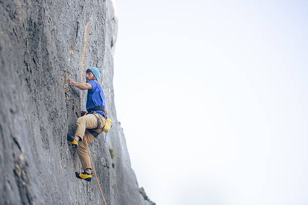 istock Man Climbing a Steep Rock Face — Side View of Rock Climber in Action 2244781064