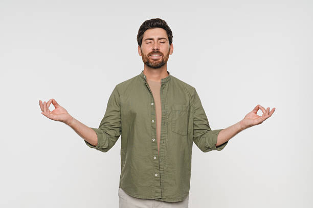 istock Young tranquil man in casual clothes standing isolated on white background makes mudra gesture meditates feels internal balance having healthy habit, wellbeing harmony no stress concept 2244781691