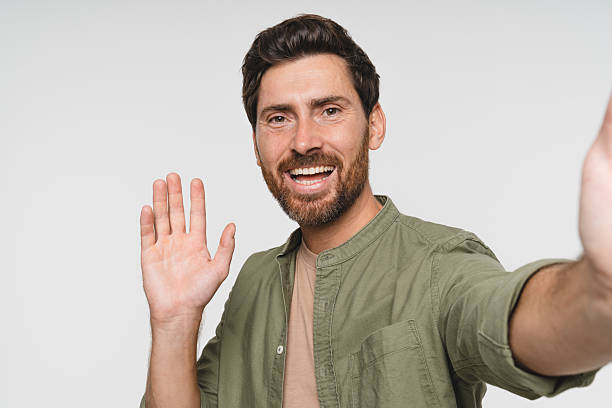 istock Close up Young smiling man in casual clothes posing isolated on white wall background, studio portrait. People sincere emotions lifestyle concept. Mock up copy space. Doing selfie shot on mobile phone 2244782033