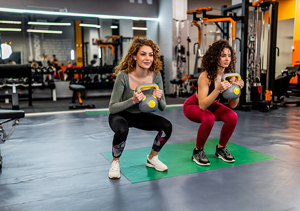 istock Women training with kettlebells performing squats in gym 2244784160