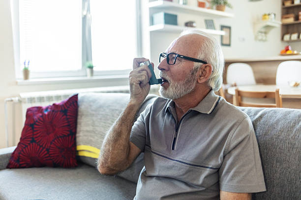 istock Senior man using asthma inhaler for relief an attack at home. Old man using asthma inhaler for preventing attack. Mature man using medical inhaler to prevent and treat wheezing and shortness of breath caused by allergy. 2244787289