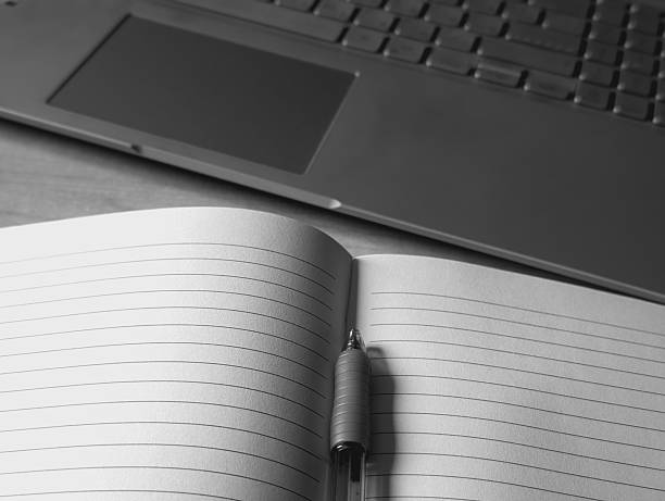 istock monochrome high-angle view of a modern laptop and open lined notebook with pen on desk for hybrid work concept 2244787418