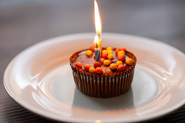 Woman's hand holding a birthday cupcake with candles at home