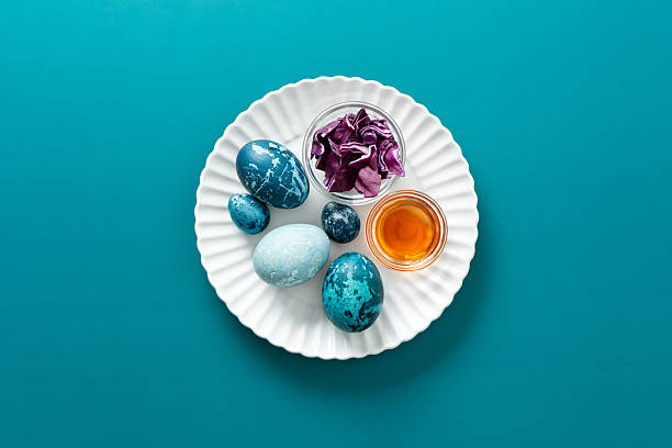 istock Brightly colored eggs are arranged on a plate alongside natural dye materials like of red cabbage and a small jar of vinegar, celebrating the joy of Easter during spring, how to dye eggs marbled blue 2244789154