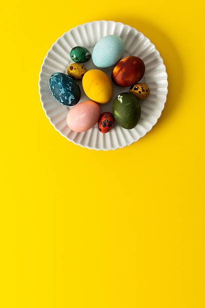 istock A white plate holds an assortment of vibrant Easter eggs in various colors, placed on a sunny yellow backdrop, perfect for a festive spring gathering 2244789160