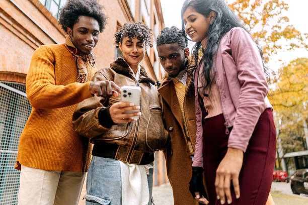 istock Cheerful group of diverse friends using smartphone outdoors 2244791954