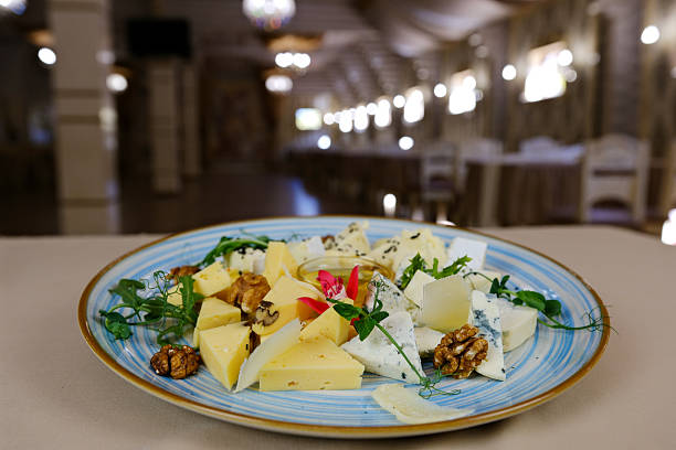 istock Cheese, bread, red wine, and walnuts on a kitchen table. In the background various wine bottles. Selective focus. 2244792098