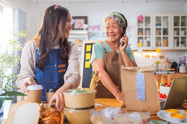 Bakery shop Asian senior woman with apron working in bakery pastry store shop checking order for delivery online purchase small business shopstore woman working in bread bakery store