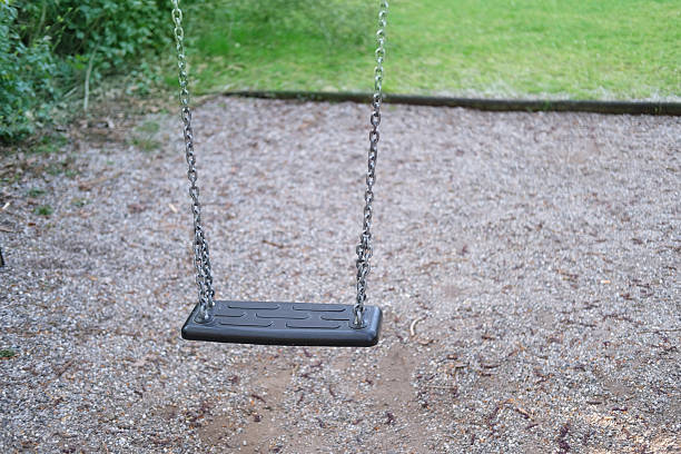 Empty swing in quiet park, no children playing, low birth rate, social concern, deserted playground, Abandoned swing set, calm atmosphere, lonely scene, social concern, nature around