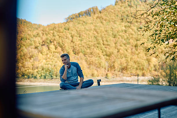 istock Mature man relaxing by lake thinking in autumn 2244795589