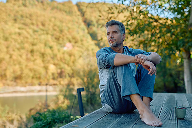 Adult Latino male sitting on the stairs of a log cabin, in a state of anxiety and depression.
