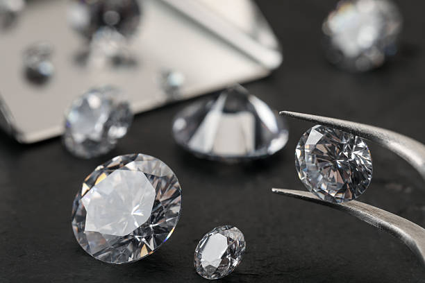 istock Tweezers with beautiful gemstones on black table, selective focus 2244795788