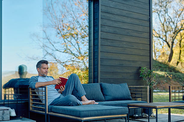 istock Man relaxing reading book on modern outdoor sofa 2244796056