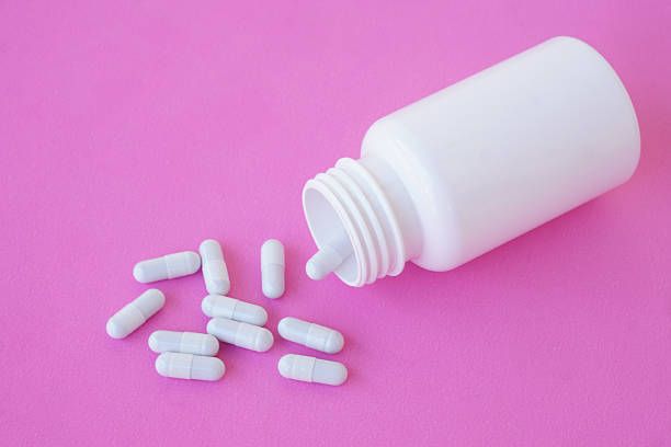 istock White medicine capsules spilling from a plastic bottle on a pink background. Minimal healthcare and pharmaceutical concept. Clean design suitable for medical, supplement, or wellness themes. 2244799945