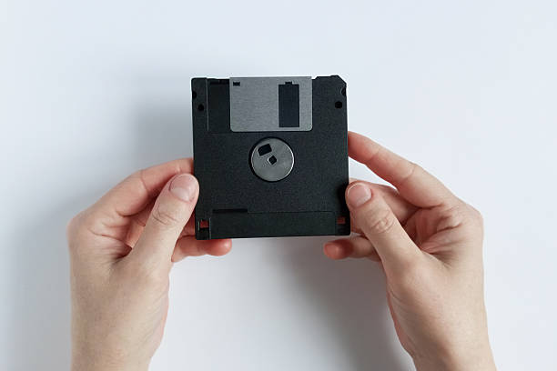 istock A Caucasian woman holds a computer floppy disk. White background. Top view. 2244803486