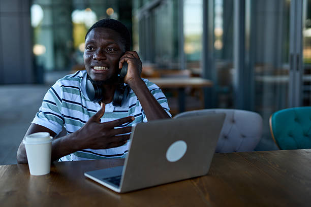 istock One black man talking on his cell phone while working outside at a cafe 2244808368