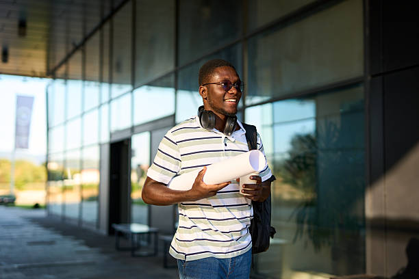istock One black man walks outside to work with a coffee in his hands and papers in a roll 2244808491