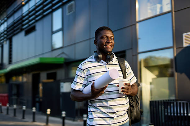 istock One black man walks outside to work with a coffee in his hands and papers in a roll 2244808537