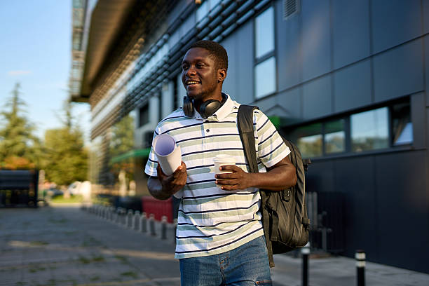 istock One black man walks outside to work with a coffee in his hands and papers in a roll 2244808545