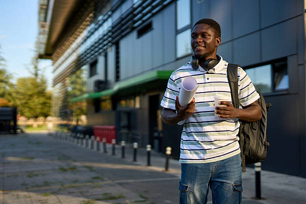 istock One black man walks outside to work with a coffee in his hands and papers in a roll 2244808546