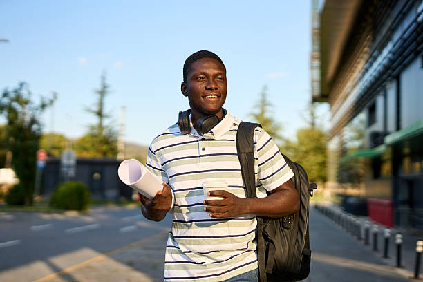 istock One black man walks outside to work with a coffee in his hands and papers in a roll 2244808561