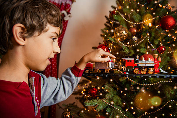 istock Boy Playing With Toy Train Near Christmas Tree 2244814417