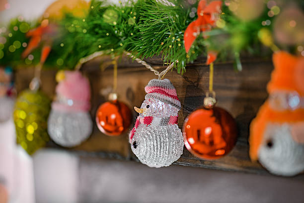 Festive close-up of Christmas decorations featuring sparkling snowman ornaments, red baubles, and a green garland with bokeh lights in the background. The warm and colorful holiday scene evokes a joyful Christmas atmosphere, perfect for themes of winter celebration, home decor, and holiday spirit.