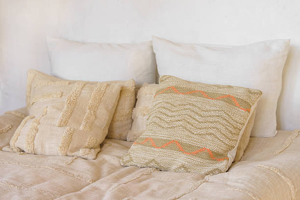 istock Soft beige pillows, decorative cushions on cozy bed with natural linen textile in bright sunlight 2244816168