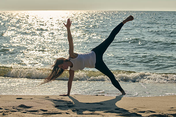 istock Woman practicing yoga side plank pose on Baltic Sea beach at sunset 2244819485