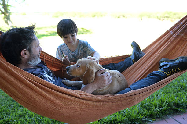 middle age father in a hammoc with his dog and his dog