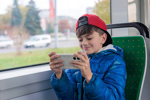istock Boy playing mobile video game on smartphone while sitting in bus, kid using phone during travel, child with gadget in public transport, technology addiction, digital lifestyle concept 2244820436