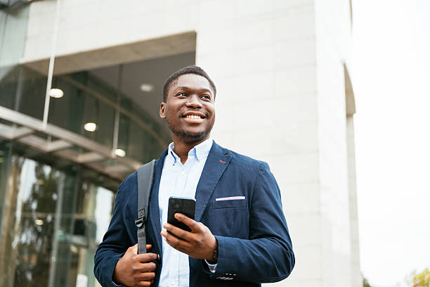 istock Young black professional on the move in modern financial district, using phone 2244822370