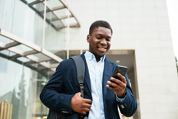 istock Young black professional on the move in modern financial district, using phone 2244822407