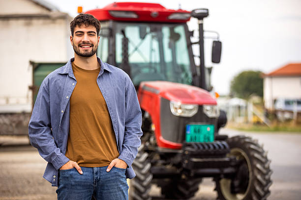 istock Young tractor driver smiling in front of tractor 2244825061