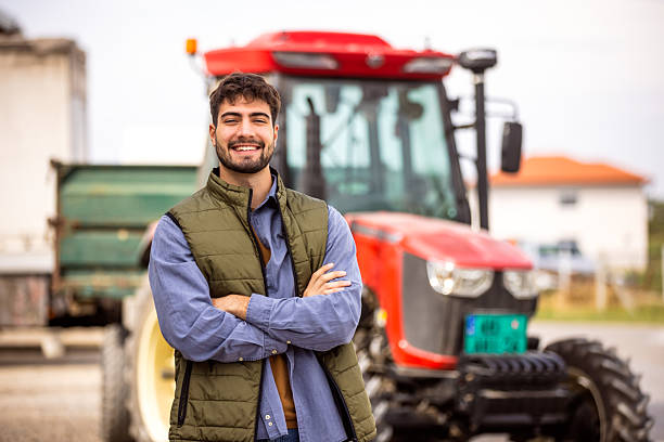 istock Young tractor driver smiling in front of tractor 2244825091