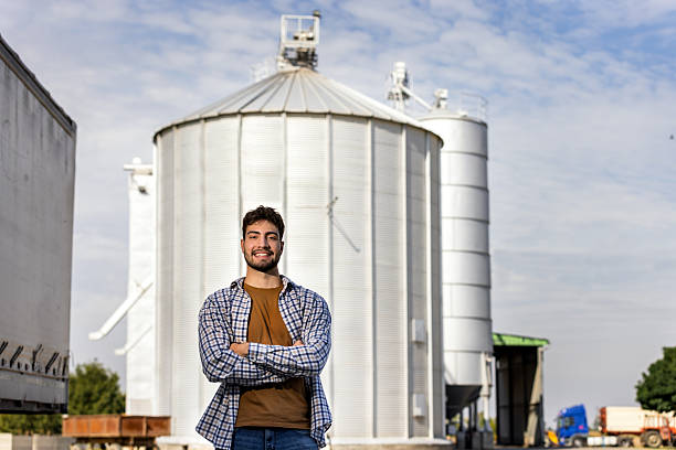 istock Young worker smiling with crossed arms in front of silo 2244825092