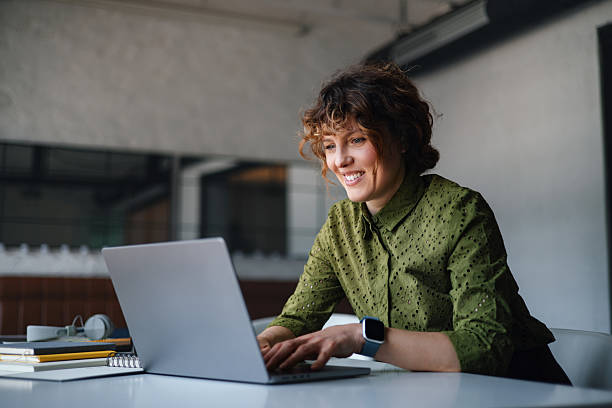 istock Focused Woman Working on Laptop in Modern Office Coworking Space, Smiling While Typing 2244825172