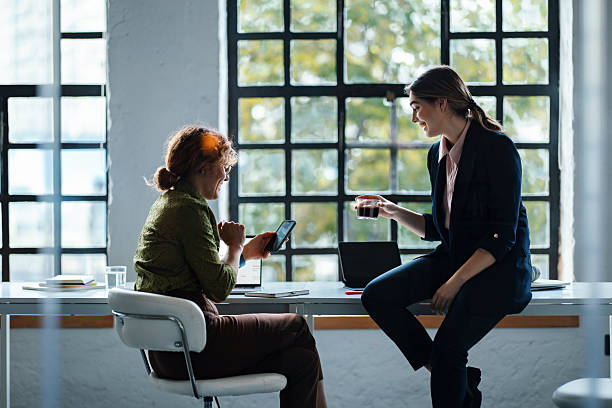 istock Professional Women Collaborating In Modern Office During Informal Meeting And Coffee Break Near Large Windows 2244825236