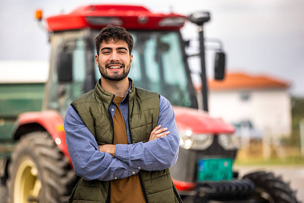 istock Young tractor driver smiling in front of tractor 2244825413