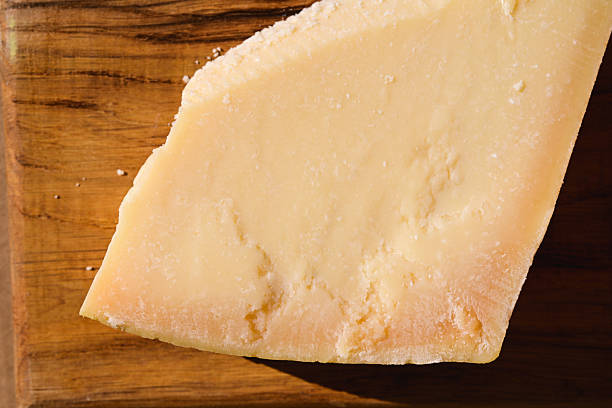 Parmesan cheese wedge resting on a rustic wooden cutting board, close-up view