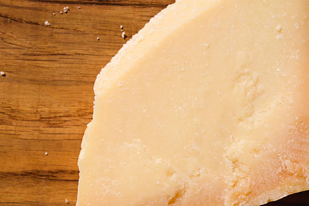 Parmesan cheese wedge resting on a rustic wooden background