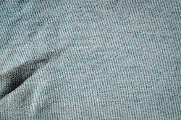 Light blue faded denim textile material showing diagonal weave pattern and crease