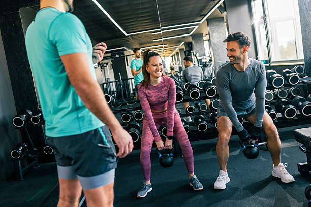 istock Young man and woman doing weighted squat with personal trainer 2244828926
