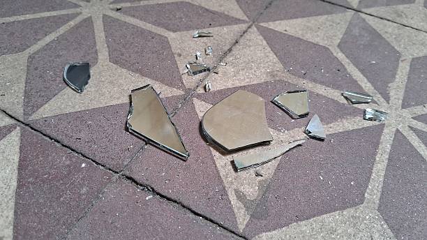 Broken glass liquor bottle on brick road.