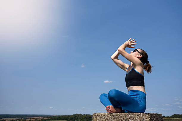 Sporty woman meditating and practicing yoga under a blue sky