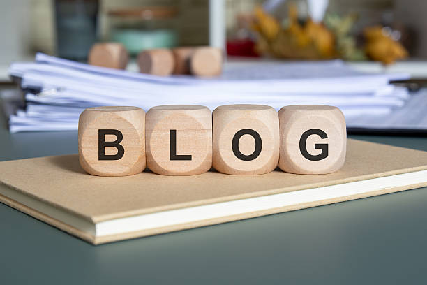 istock Wooden cubes spelling BLOG on a notebook with stacked documents, symbolising content creation. 2244836292