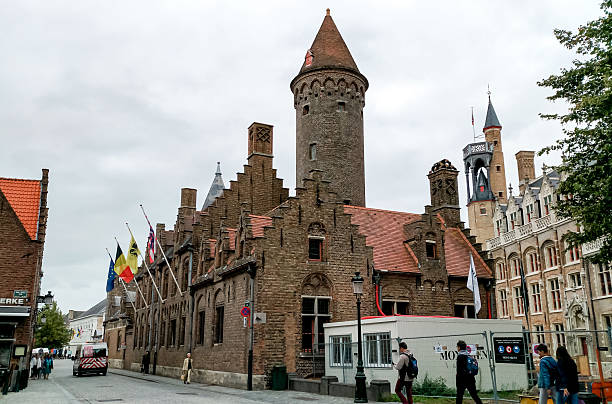 Brugge, Belgium - August 27, 2018 - Medieval brick architecture in bruges on overcast day with flags and tourists.